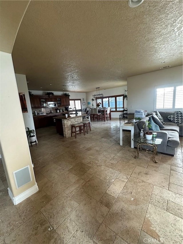 interior space featuring a textured ceiling, visible vents, and stone tile flooring