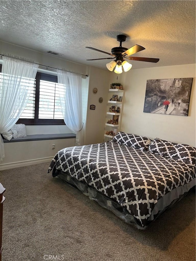 bedroom with a textured ceiling, carpet flooring, a ceiling fan, visible vents, and baseboards