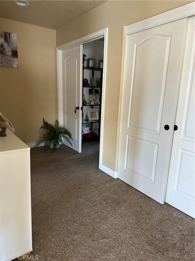 unfurnished bedroom with dark colored carpet and a closet