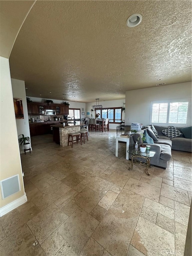 interior space featuring arched walkways, baseboards, a textured ceiling, and stone tile floors