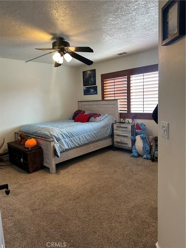 carpeted bedroom featuring a textured ceiling, ceiling fan, and visible vents