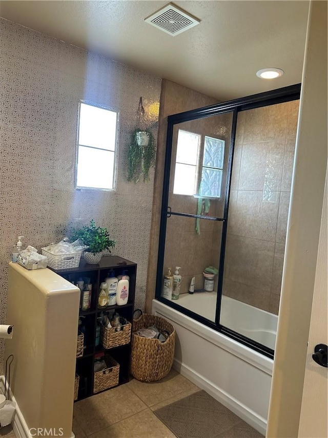 full bathroom featuring shower / bath combination with glass door, visible vents, and tile patterned floors