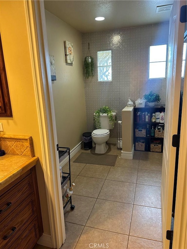 bathroom with visible vents, toilet, vanity, baseboards, and tile patterned floors