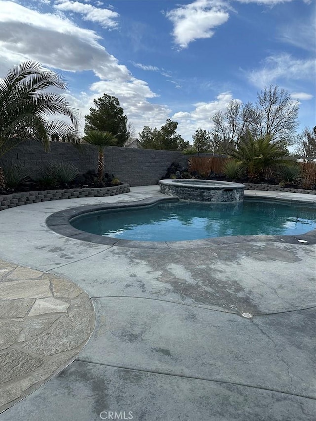 view of pool featuring a fenced backyard and a pool with connected hot tub