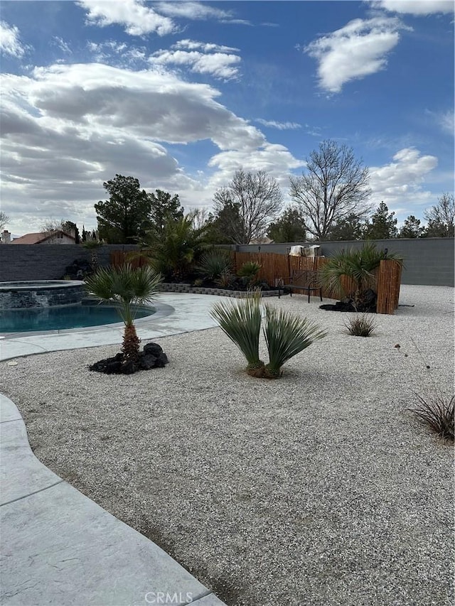 view of yard featuring a fenced in pool, fence, and an in ground hot tub