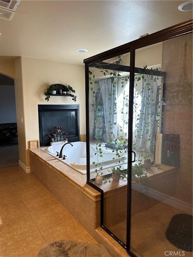 full bathroom featuring a stall shower, a garden tub, a glass covered fireplace, and visible vents