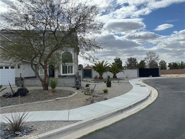 view of front of home with stone siding, fence, a gate, and stucco siding