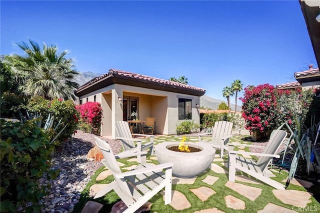 back of property with a mountain view, a patio, and an outdoor fire pit