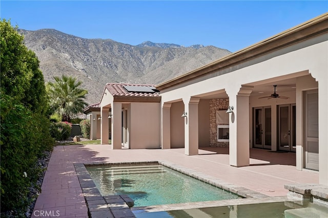 view of pool featuring an outdoor fireplace, ceiling fan, a mountain view, and a patio