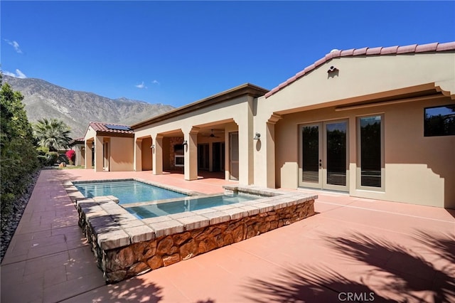 view of swimming pool with a mountain view, french doors, a patio, and an in ground hot tub