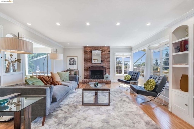 living room with a brick fireplace, ornamental molding, and light hardwood / wood-style floors