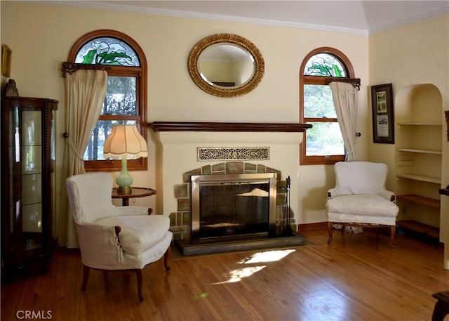 sitting room with hardwood / wood-style flooring, crown molding, and a tiled fireplace