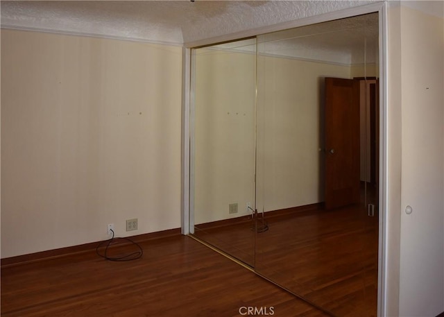 unfurnished bedroom with wood-type flooring, a textured ceiling, and a closet