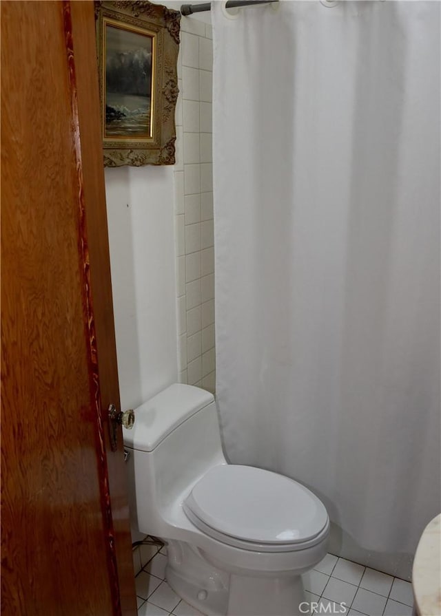 bathroom featuring curtained shower, tile patterned flooring, and toilet