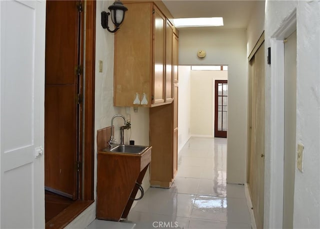 corridor featuring light tile patterned floors and sink