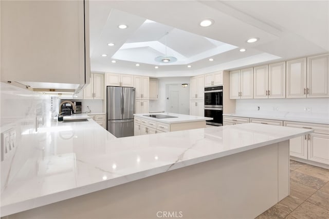 kitchen featuring sink, a tray ceiling, kitchen peninsula, and black appliances