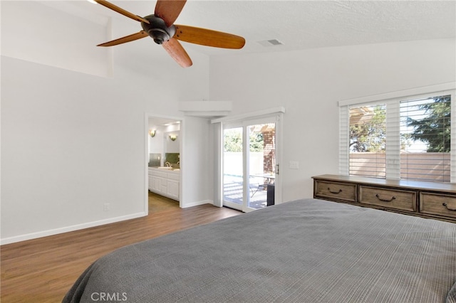 bedroom featuring hardwood / wood-style flooring, access to exterior, high vaulted ceiling, connected bathroom, and ceiling fan