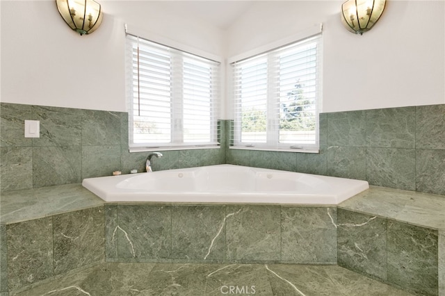 bathroom featuring a healthy amount of sunlight, tiled tub, and vaulted ceiling