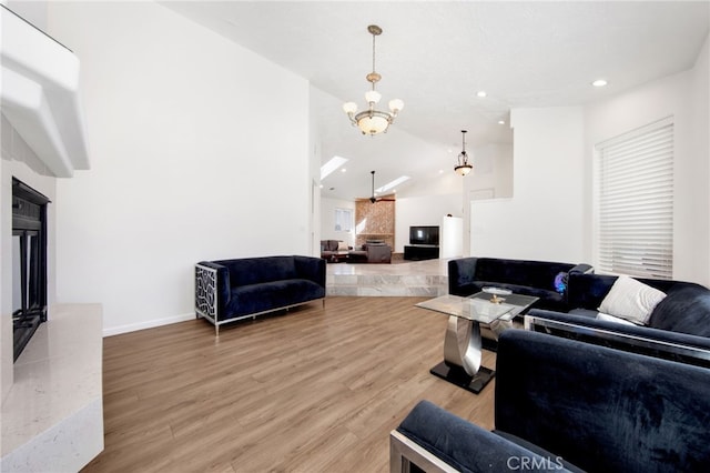 living room featuring vaulted ceiling with skylight, a chandelier, and hardwood / wood-style floors