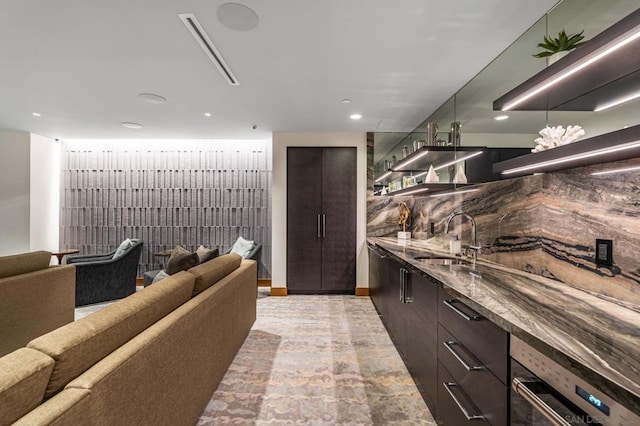 kitchen with sink, dark brown cabinetry, and dark stone counters