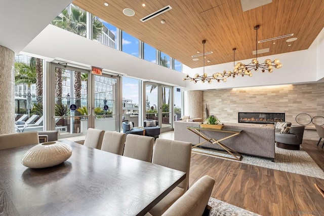 dining space with wooden ceiling, a towering ceiling, hardwood / wood-style floors, and a notable chandelier