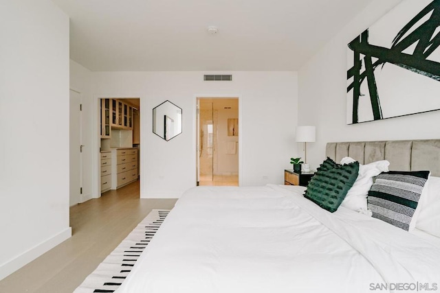 bedroom with ensuite bathroom and light hardwood / wood-style floors