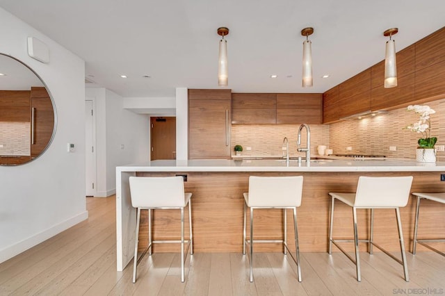 kitchen featuring a kitchen bar, tasteful backsplash, hanging light fixtures, and sink