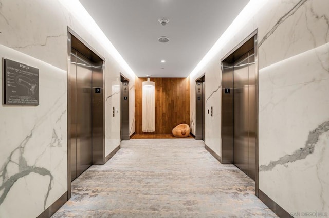 corridor featuring elevator and wooden walls