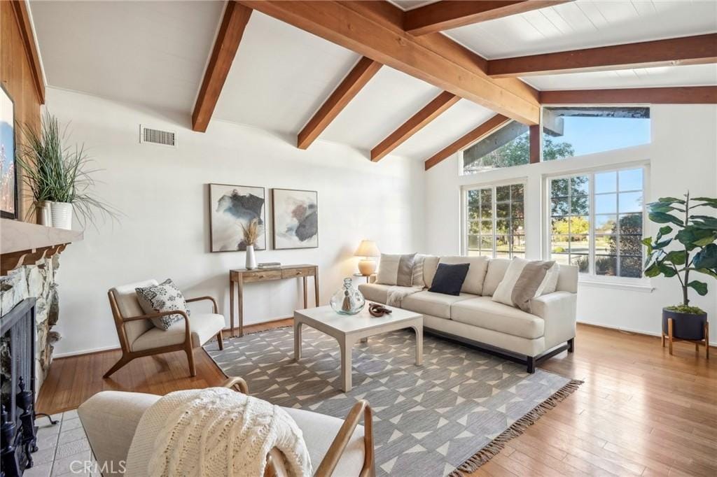 living room featuring lofted ceiling with beams, wood-type flooring, and a fireplace