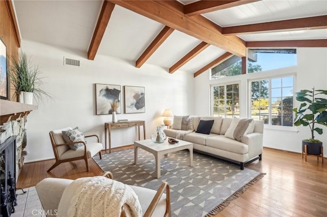 living room featuring lofted ceiling with beams, wood-type flooring, and a fireplace