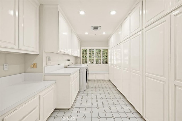 clothes washing area featuring cabinets and independent washer and dryer