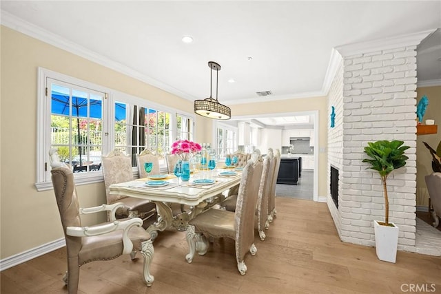 dining area with a fireplace, light hardwood / wood-style floors, and ornamental molding