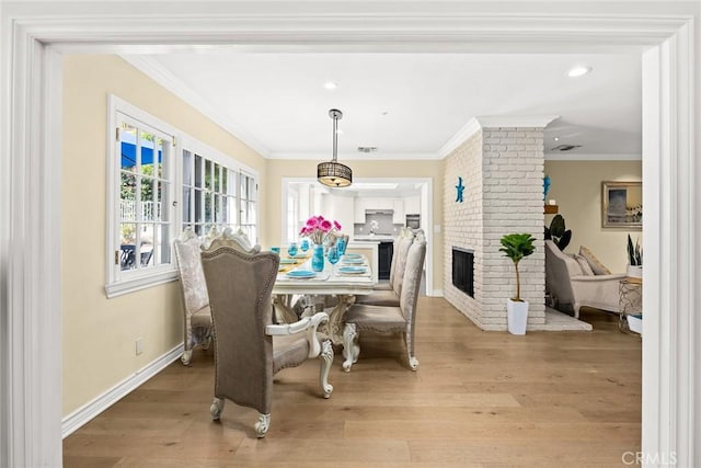 dining area with light hardwood / wood-style floors, ornamental molding, and a fireplace