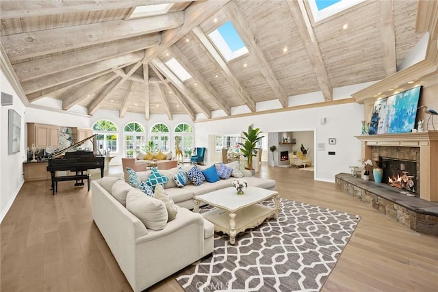 living room with beamed ceiling, hardwood / wood-style floors, high vaulted ceiling, and a stone fireplace