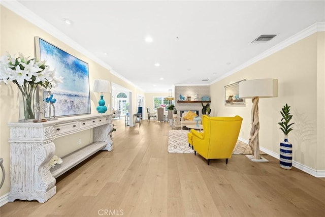 interior space featuring ornamental molding, light hardwood / wood-style floors, and a brick fireplace