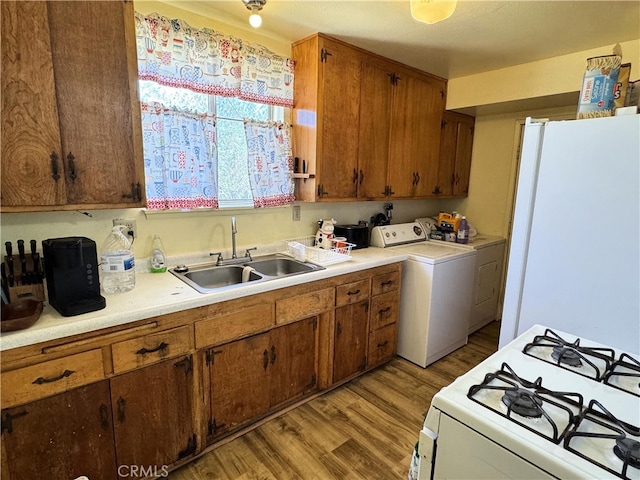 kitchen featuring white appliances, washer / clothes dryer, light hardwood / wood-style floors, and sink