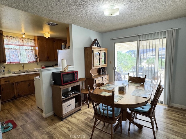 dining room with a textured ceiling, wood-type flooring, and sink