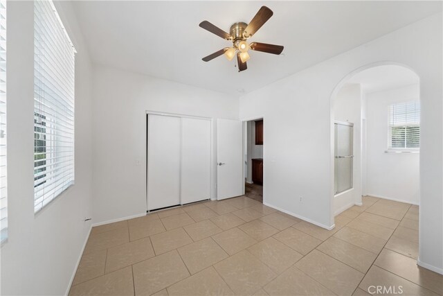 unfurnished bedroom with light tile patterned floors, ceiling fan, and a closet