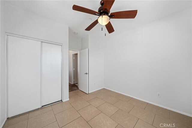 unfurnished bedroom with light tile patterned flooring, ceiling fan, and a closet