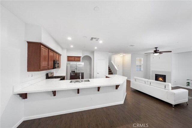 kitchen featuring a breakfast bar, kitchen peninsula, appliances with stainless steel finishes, and dark hardwood / wood-style floors