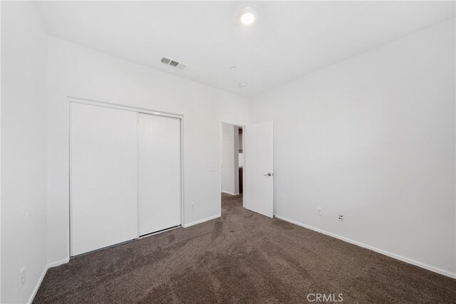 unfurnished bedroom featuring dark colored carpet and a closet