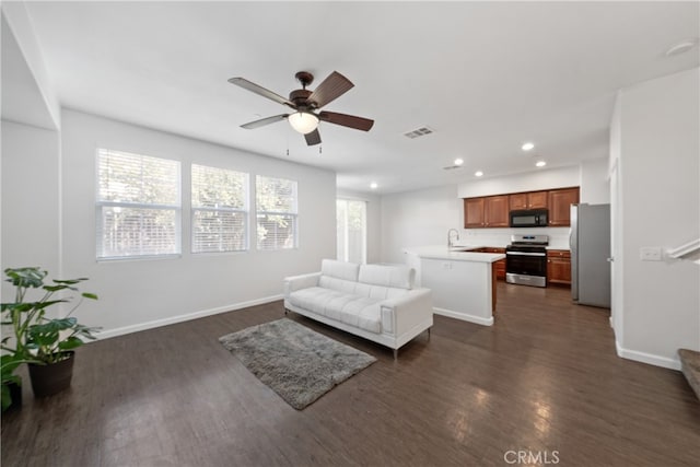 living room featuring dark hardwood / wood-style flooring, ceiling fan, and sink