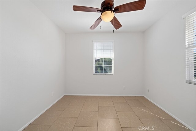 empty room with ceiling fan, light tile patterned floors, and a wealth of natural light