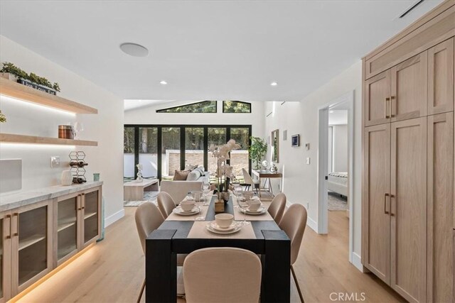 dining area with light hardwood / wood-style floors and vaulted ceiling