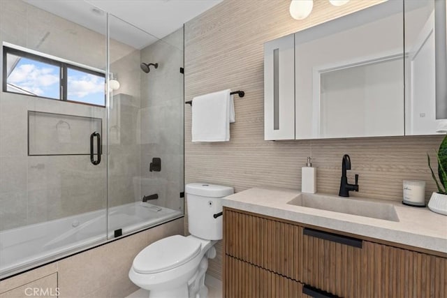 full bathroom with vanity, toilet, bath / shower combo with glass door, and decorative backsplash