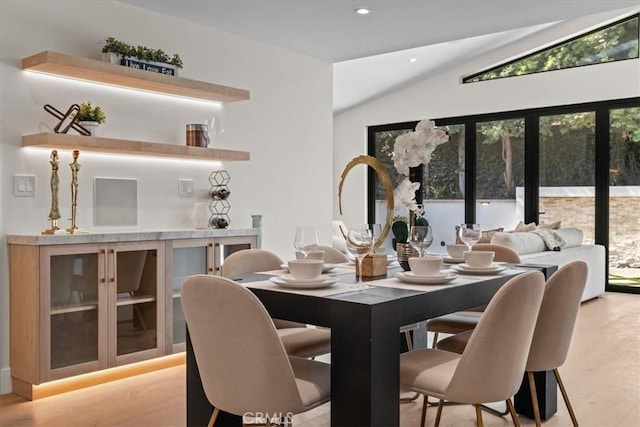 dining room with light hardwood / wood-style flooring and lofted ceiling