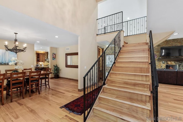 stairway with a high ceiling, hardwood / wood-style flooring, and an inviting chandelier