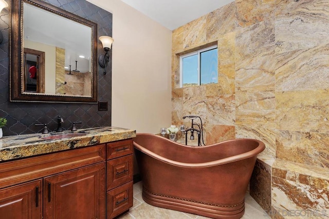 bathroom featuring a bathtub, tile patterned floors, tile walls, and vanity