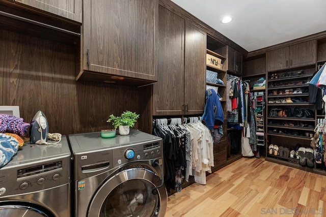 clothes washing area with cabinets, light wood-type flooring, and washing machine and dryer