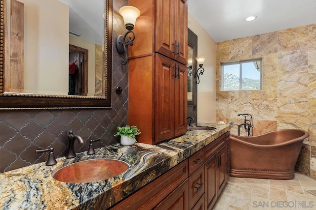 bathroom featuring backsplash, a washtub, and vanity